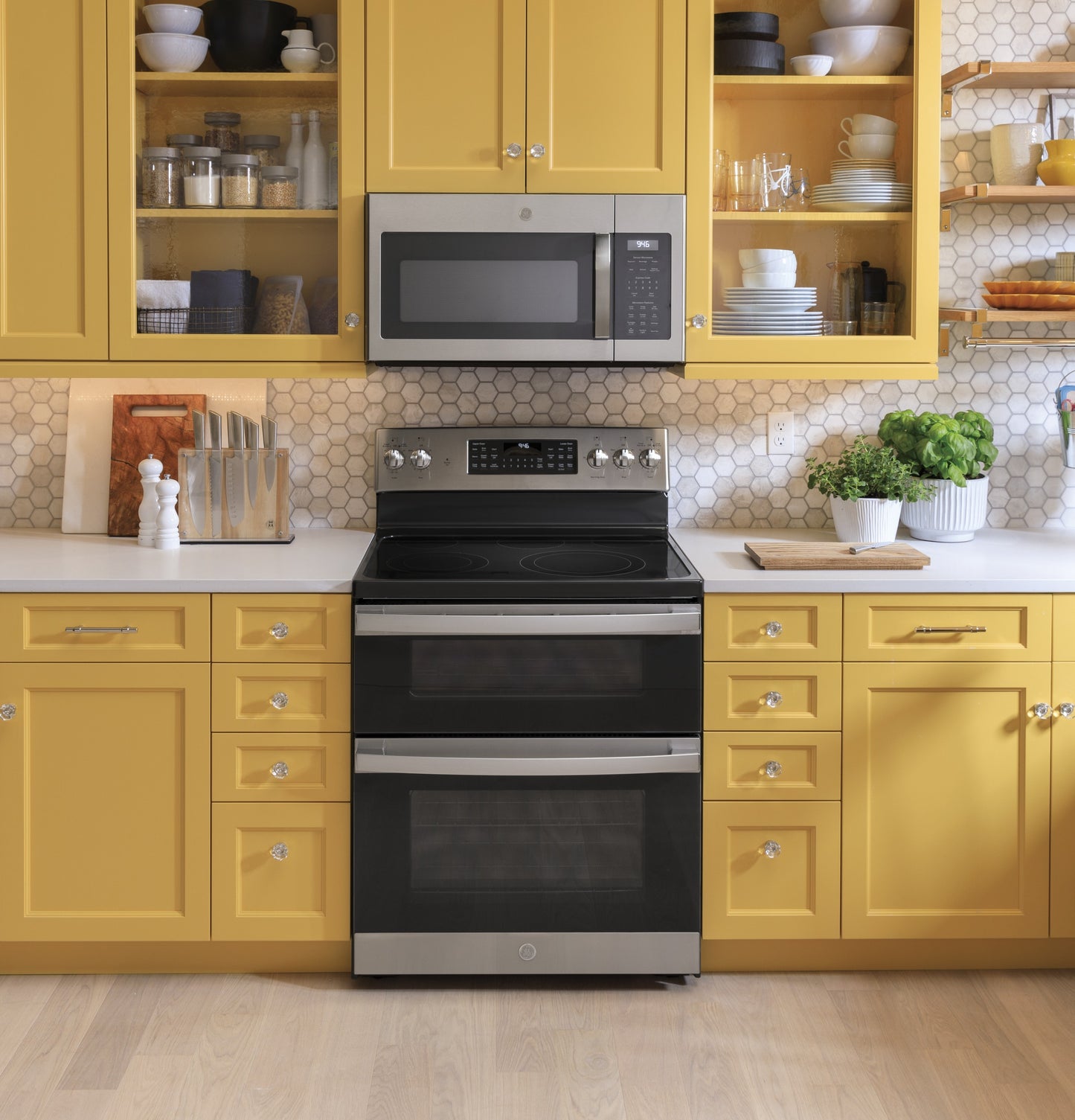 Modern kitchen with yellow cabinets featuring a fingerprint resistant over-the-range microwave and stainless steel double oven range