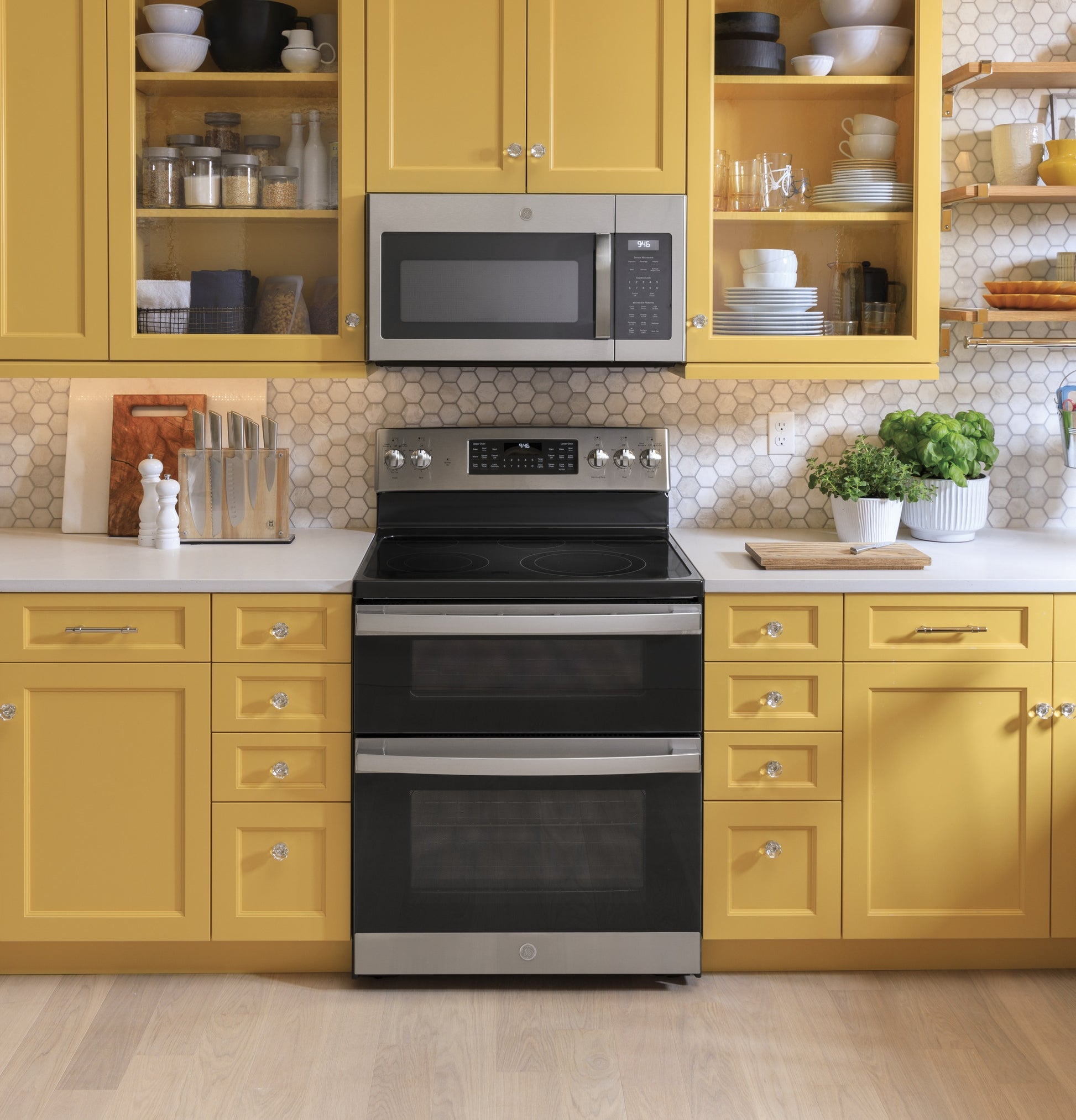 Modern kitchen with yellow cabinets featuring a fingerprint resistant over-the-range microwave and stainless steel double oven range