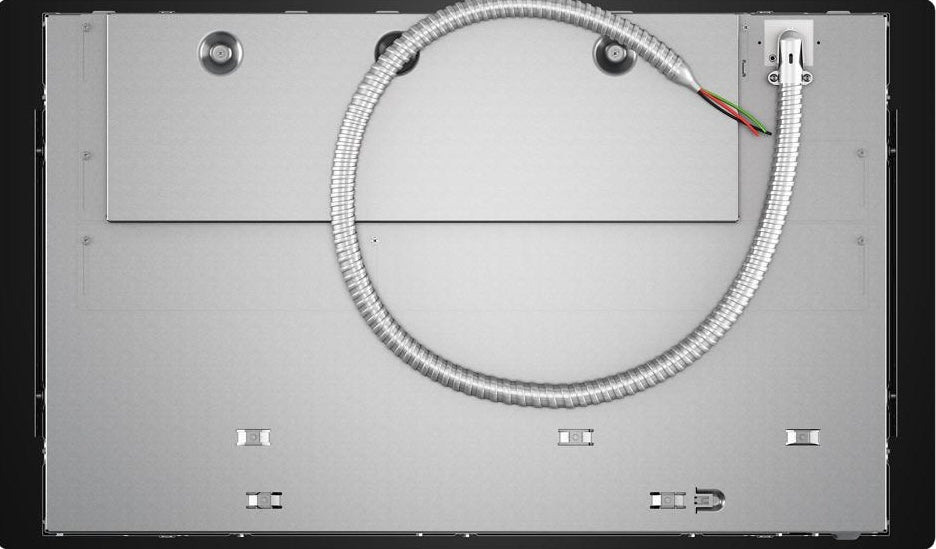 Underside view of stainless steel induction cooktop with connectivity wiring and metal protective covering in appliance setting