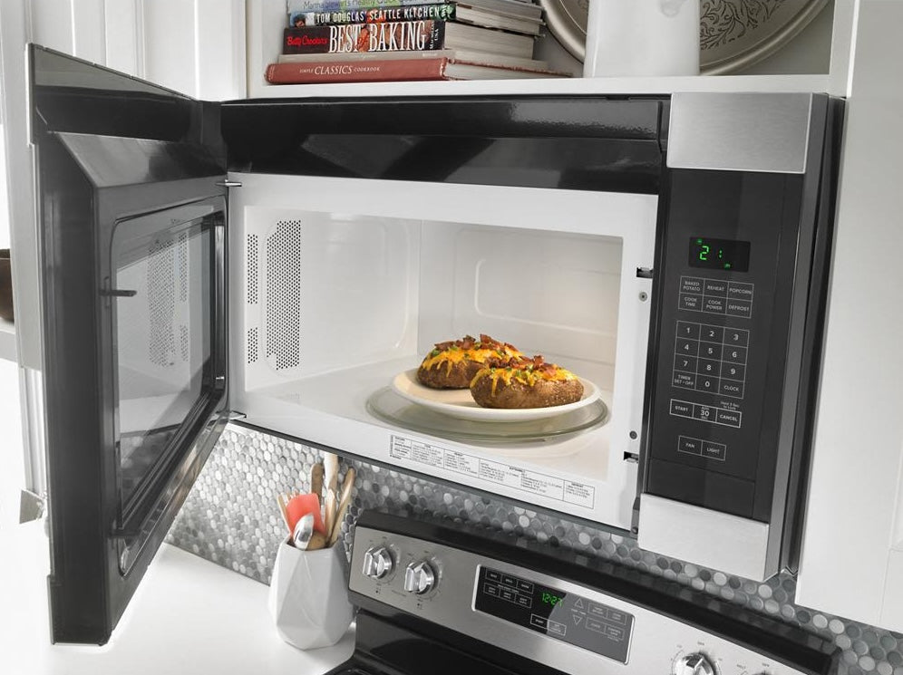 Stainless steel over-the-range microwave with digital keypad and open door in kitchen appliances collection