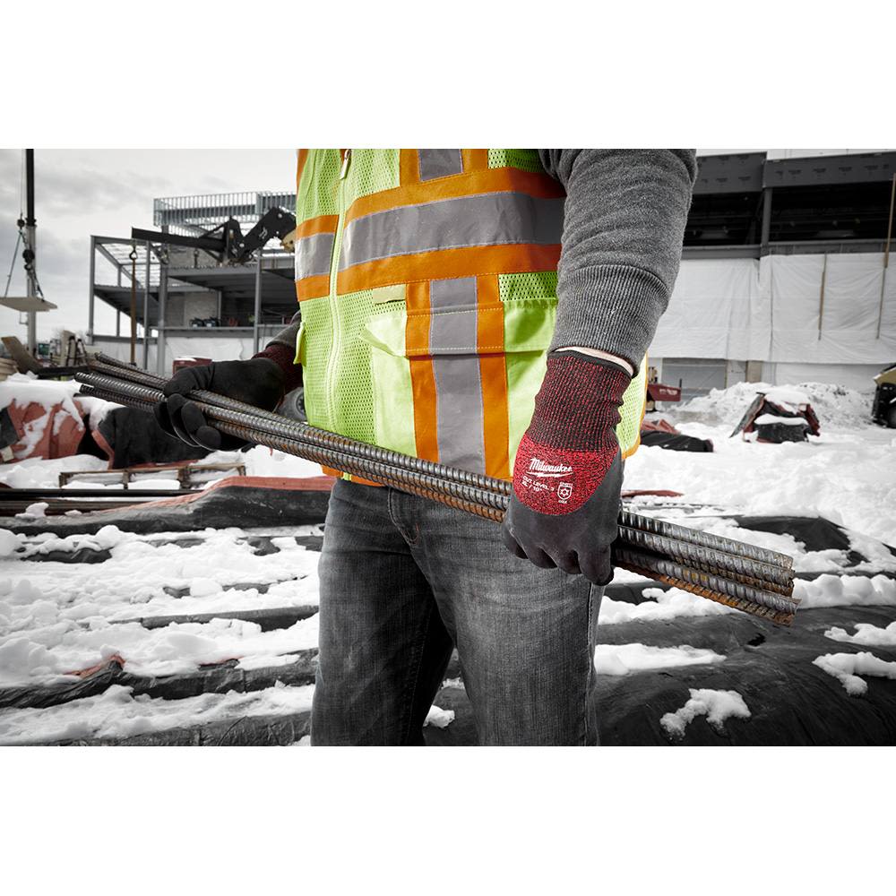 Person wearing red and black cut-resistant gloves gripping steel rebar at a snowy outdoor construction site