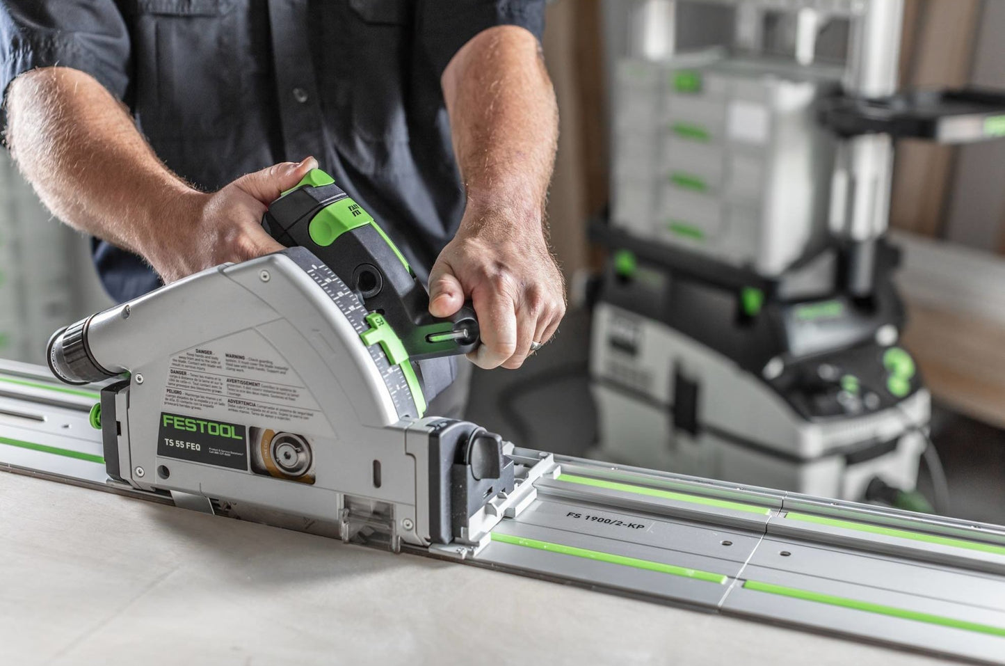 Person using Festool plunge-cut track saw with precise control on guide rail in a workshop setting