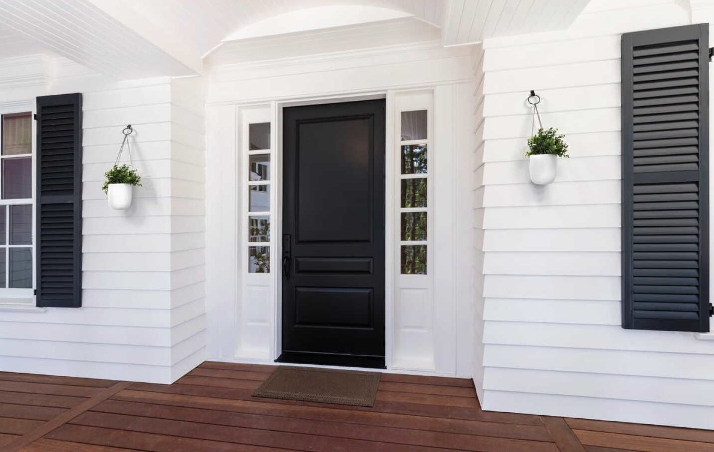Black steel siding hooks holding white hanging planters on a white house exterior for home improvement tasks