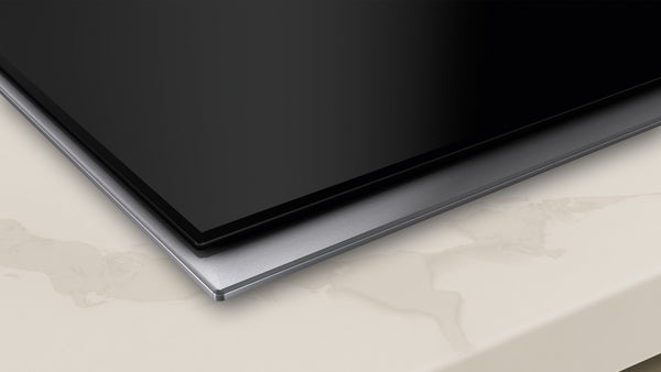 Close-up of a sleek black touch control electric cooktop surface mount with polished frame from Kitchen & Kitchenware.