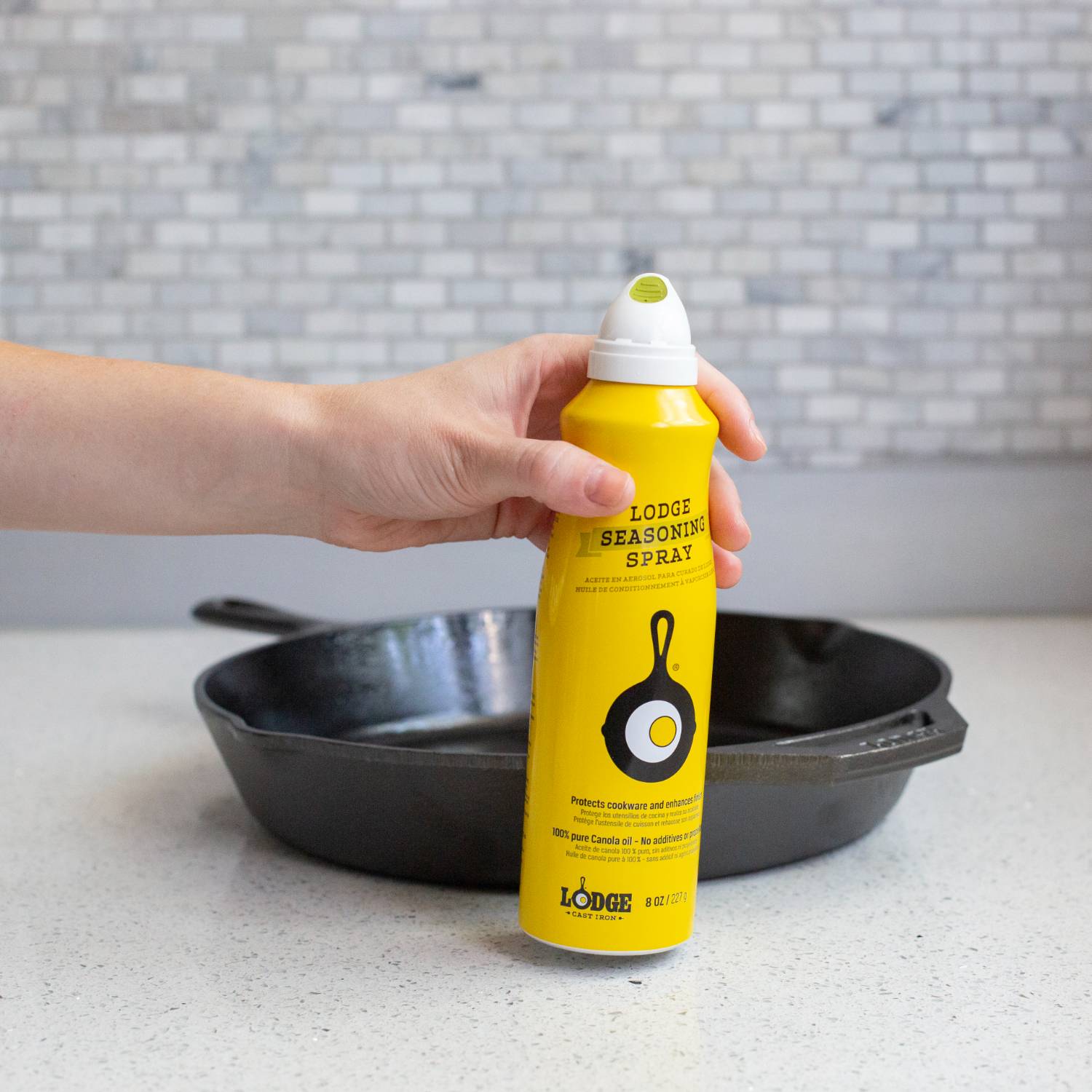 Yellow seasoning spray bottle with cast iron skillet and egg graphic held over black cast iron pan for kitchenware collections under $50