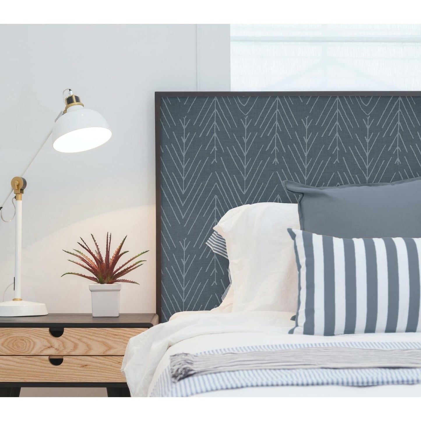 Modern bedroom featuring navy blue wallpaper with twig pattern as a backdrop for bed and bedside table decor