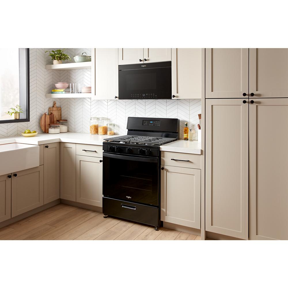 Black over-the-range microwave with digital display installed above matching freestanding oven in bright kitchen setting