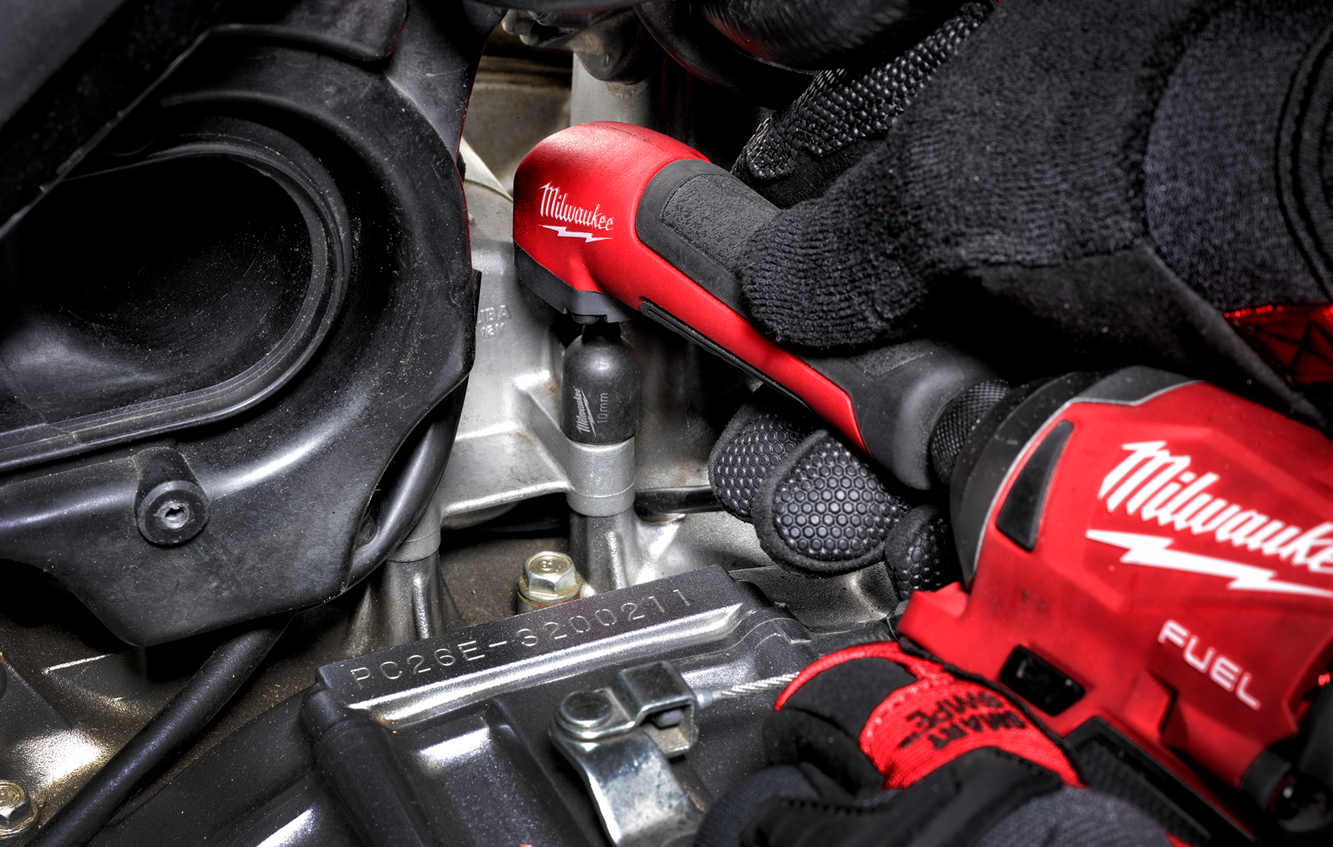 Gloved hand using red Milwaukee SHOCKWAVE™ right angle adapter for power tool tasks in home improvement collection