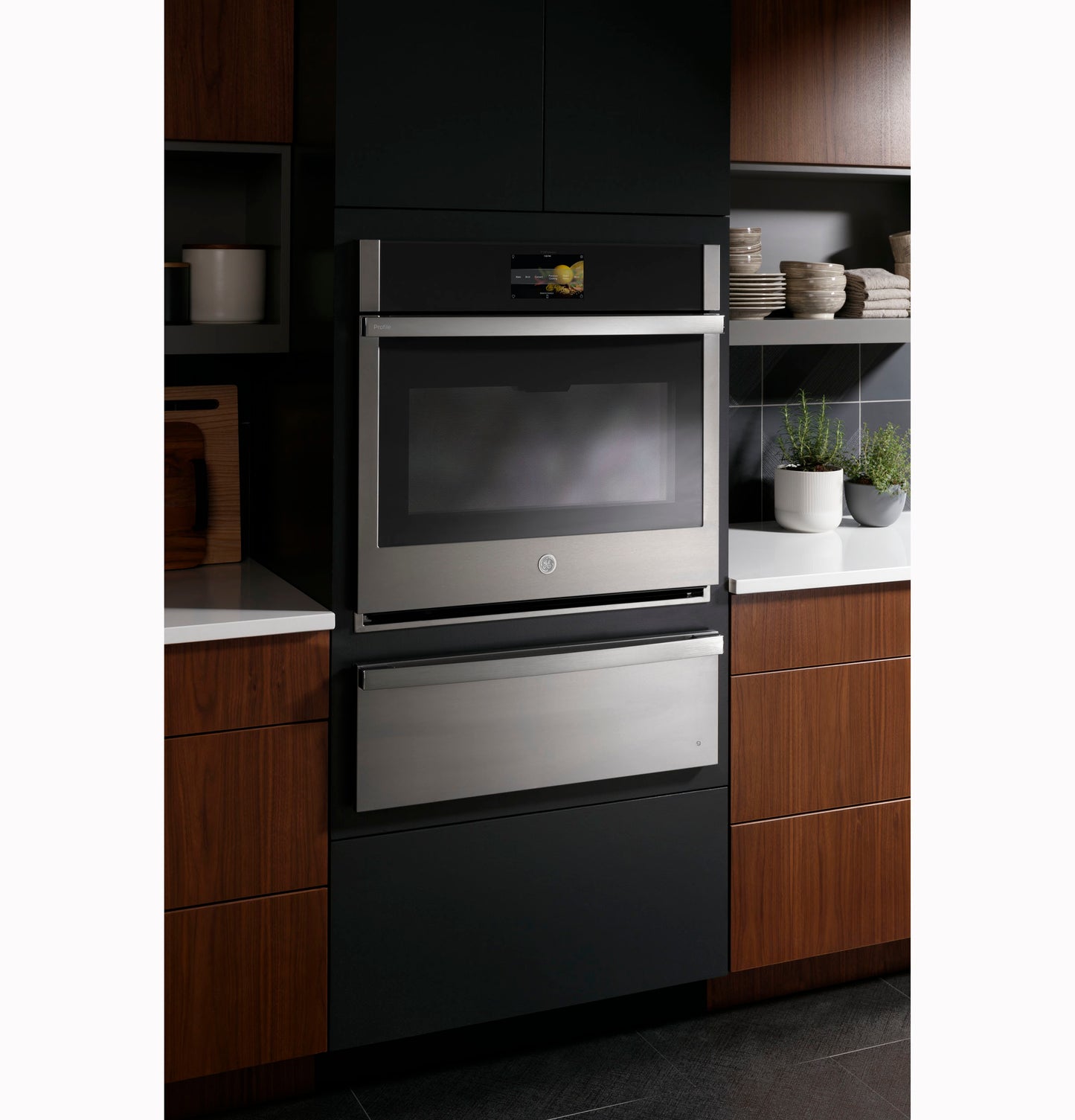 Built-in stainless steel wall oven with integrated warming drawer in modern kitchen cabinetry setting