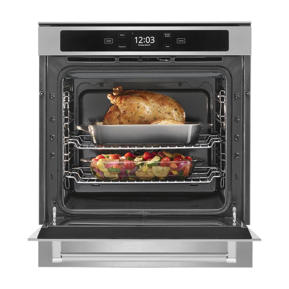 Open stainless steel oven with roasted chicken and vegetables cooking on two racks inside a smart wall oven