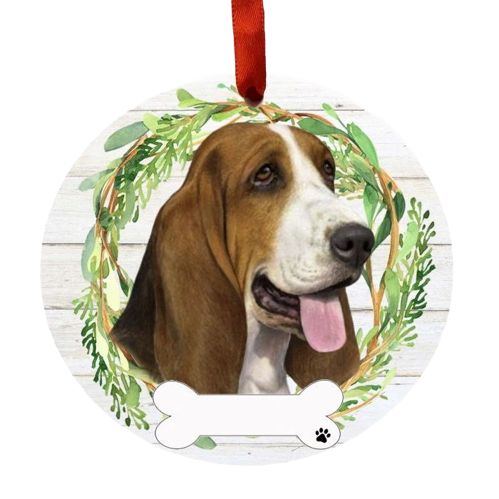 Round ornament with a happy Basset Hound face surrounded by green wreath on a rustic white wood background
