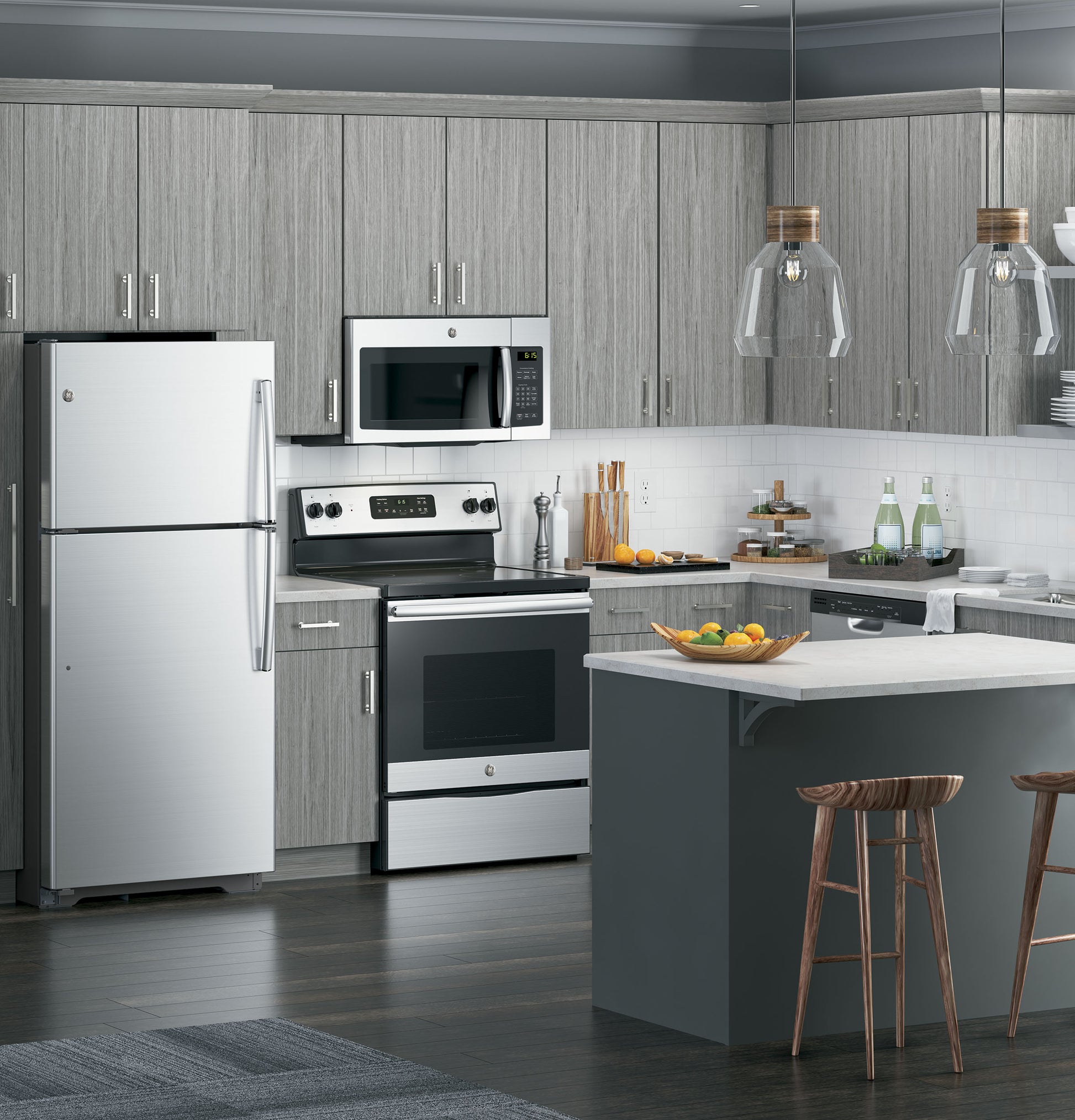 Contemporary kitchen with gray cabinetry, stainless steel microwave, refrigerator, stove, and island with wooden stools in appliances setting