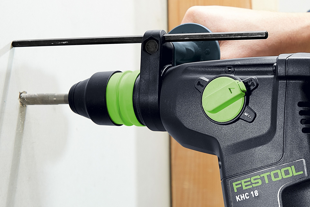 Cordless rotary hammer drill with green mode dial drilling into wall for woodworking and power tool use