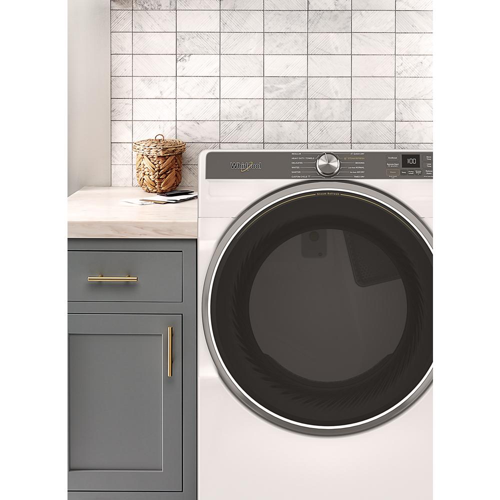 Front load gas dryer with digital cycle dial and large tinted door set beside gray cabinetry in laundry room from Dryers collection
