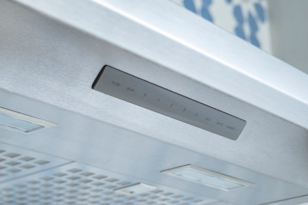 Close-up of a stainless steel control panel on a pyramid chimney wall hood with touch-sensitive buttons and built-in lighting