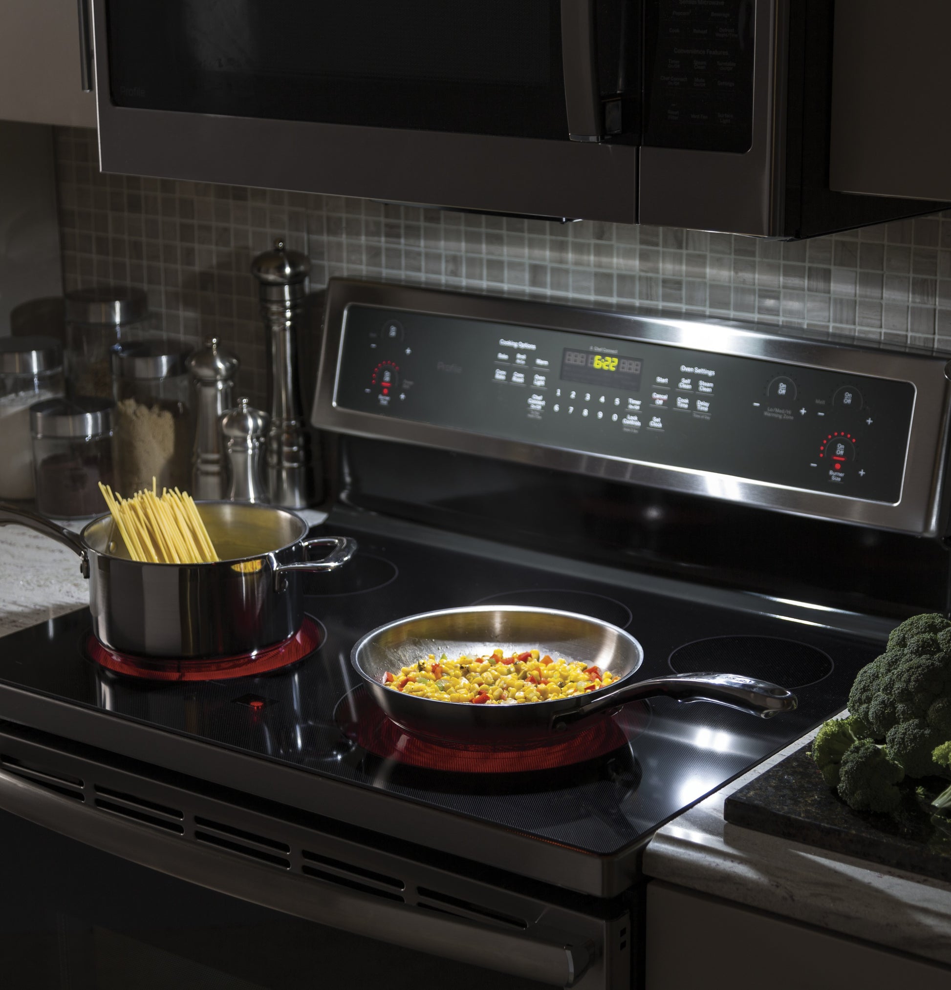 Modern electric range with digital control panel, cooking pots on active burners, in contemporary kitchenware setting