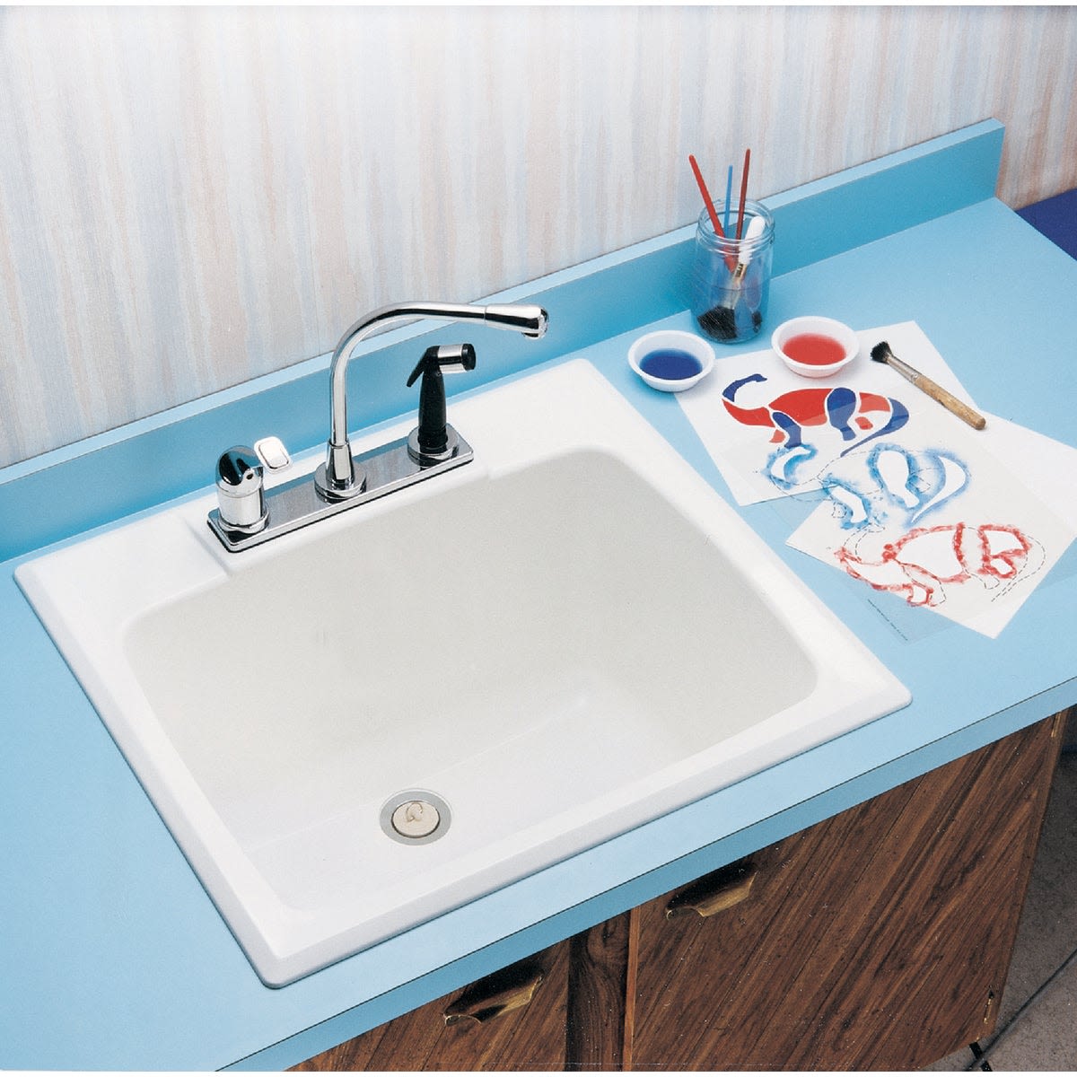 White countertop sink with chrome faucet installed on blue laminate surface next to watercolor painting supplies for home improvement