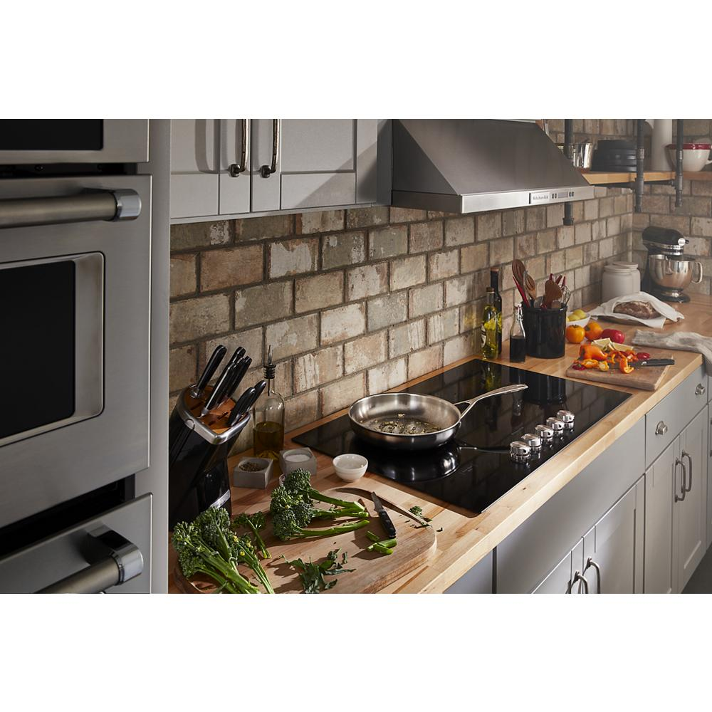 Modern kitchen scene with black electric cooktop featuring five radiant elements and stainless steel controls