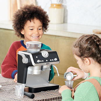Children enjoying play with black and silver Casdon Barista coffee machine toy in a bright kitchen setting