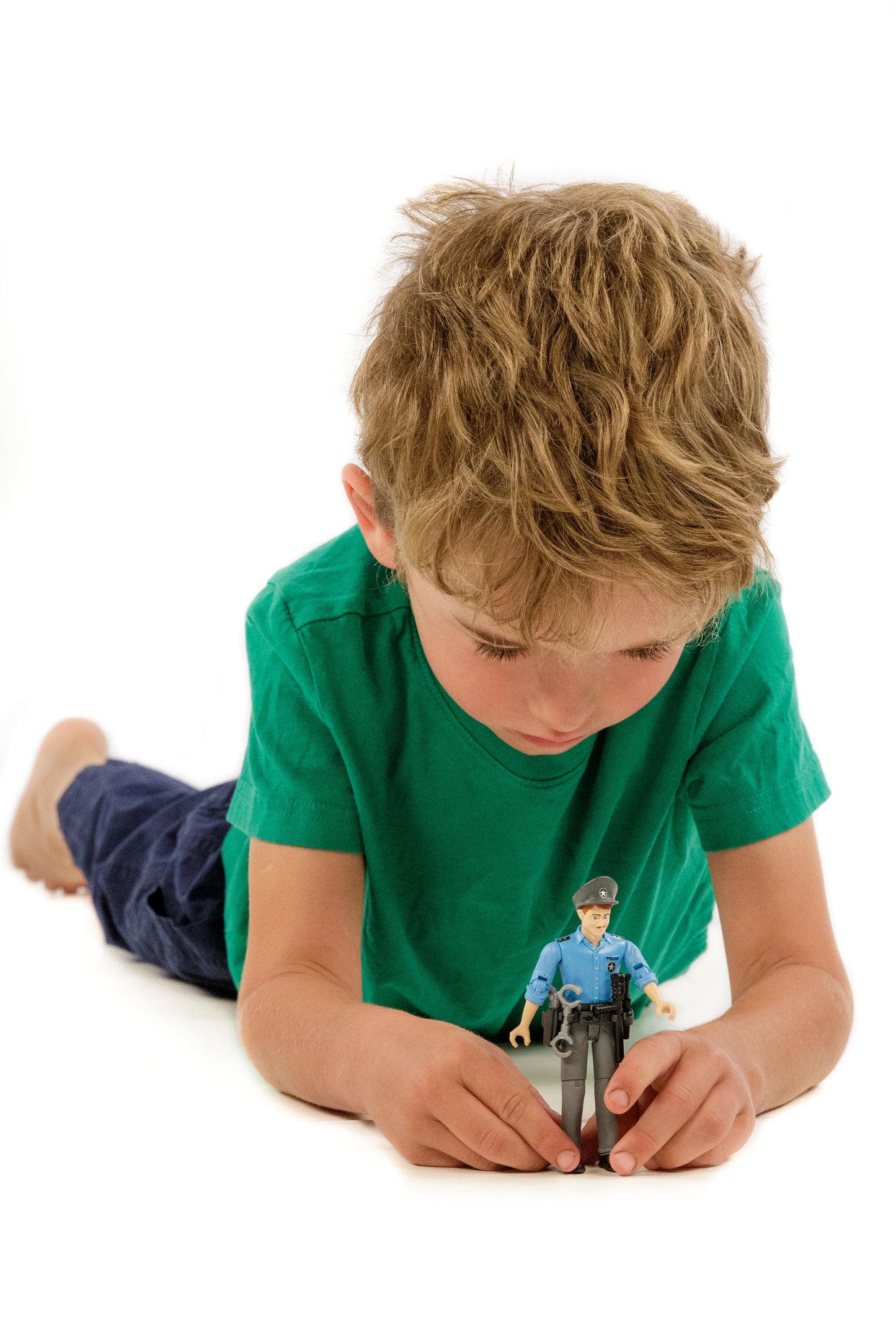 Child wearing green shirt playing with light skin police figure dressed in blue shirt and gray pants with accessories