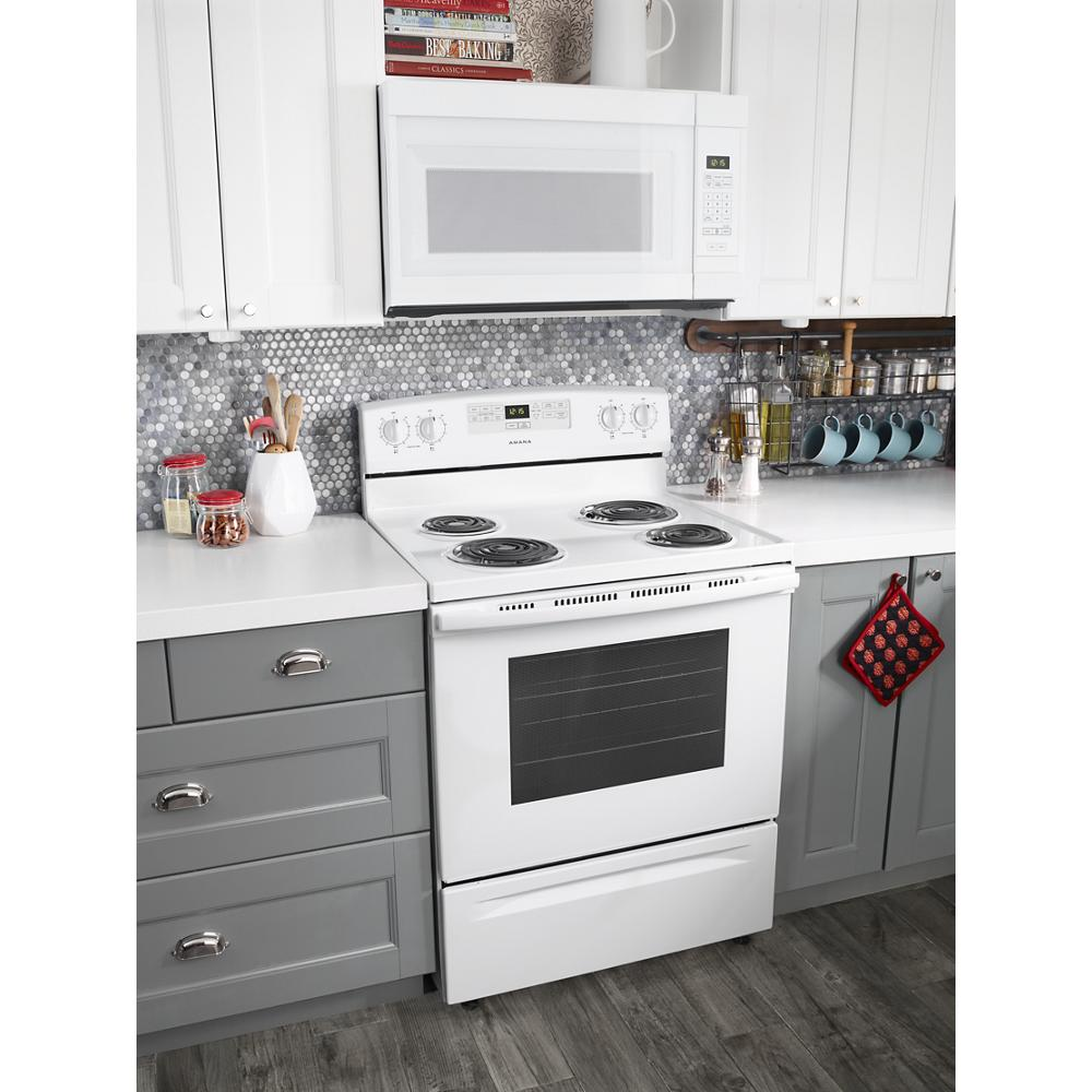 Freestanding white electric range with coil burners in a modern kitchen featuring gray cabinets and white countertops