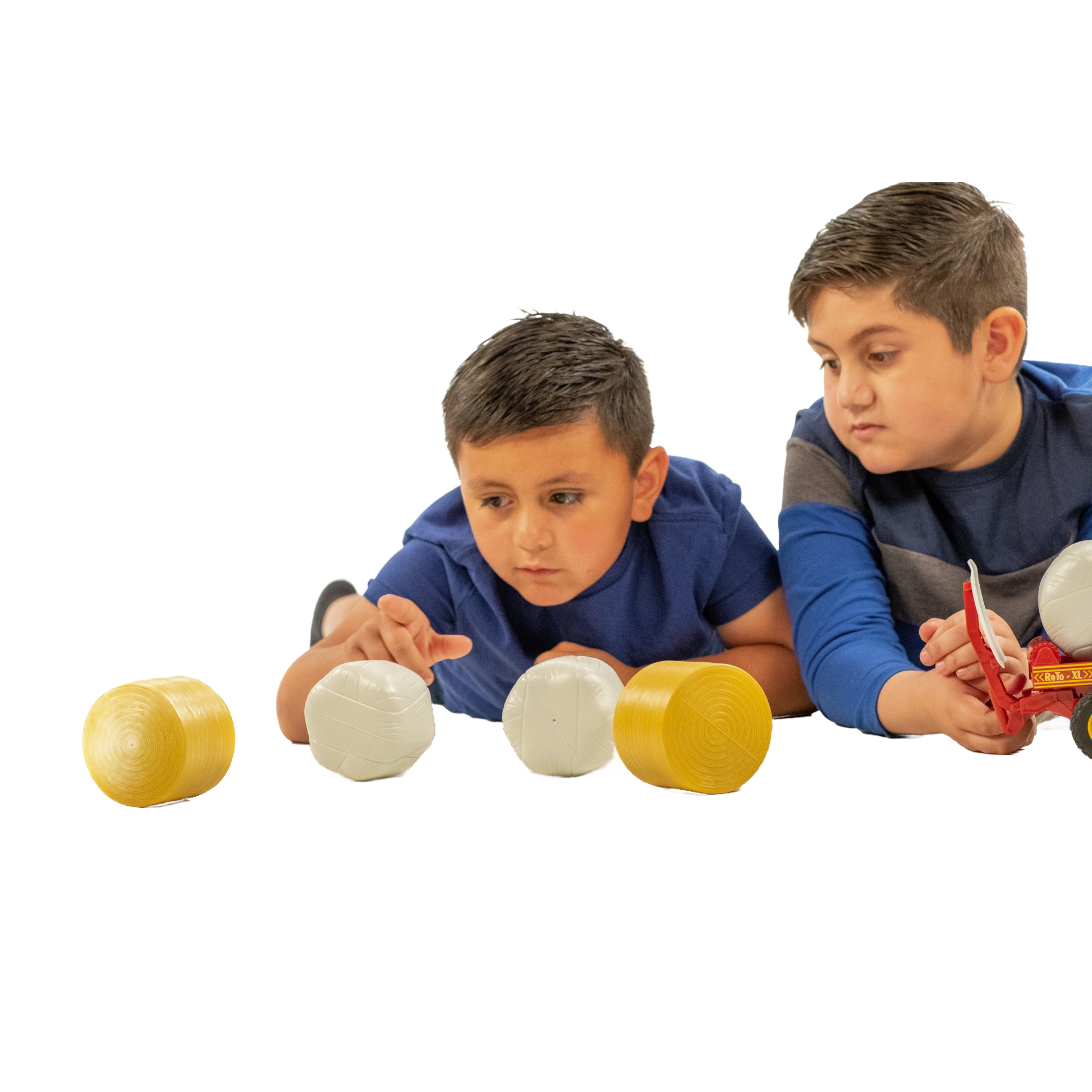Two boys playing with a set of four toy round bales in yellow and white from Bruder Toys collection under $50