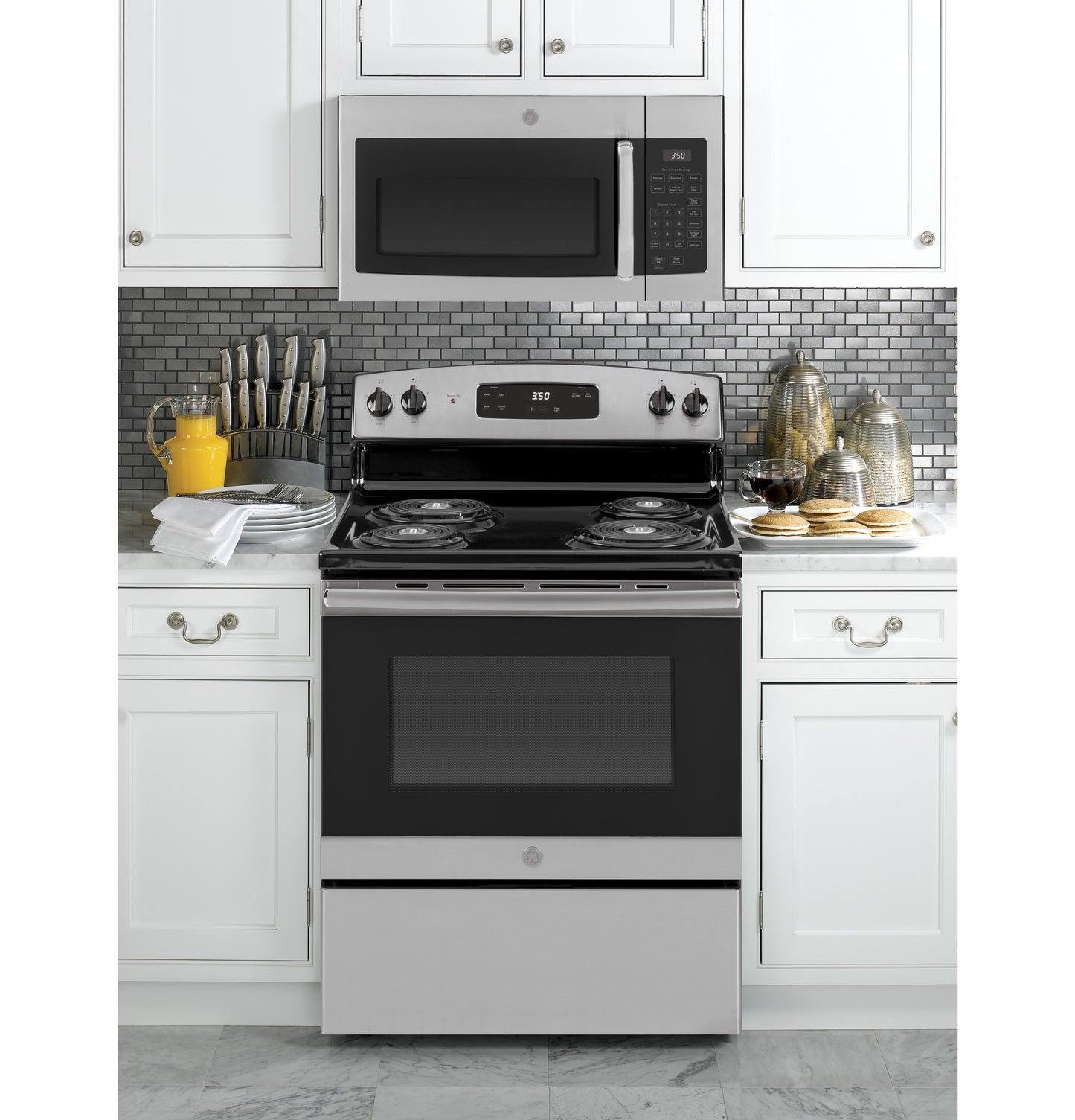 Stainless steel electric range with coil burners and control panel under matching over-the-range microwave in modern kitchen setting