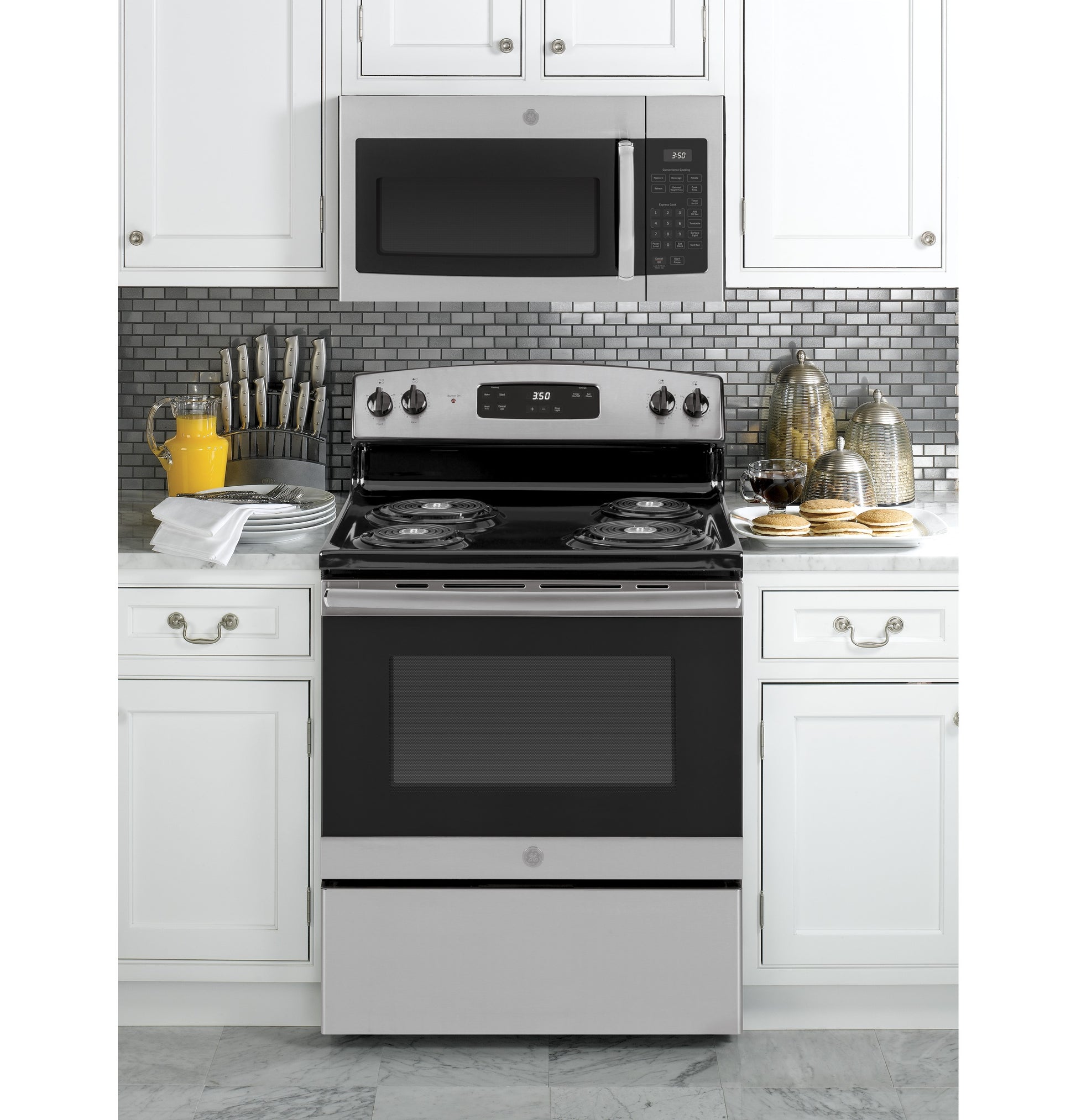 Stainless steel electric range with coil burners and control panel under matching over-the-range microwave in modern kitchen setting