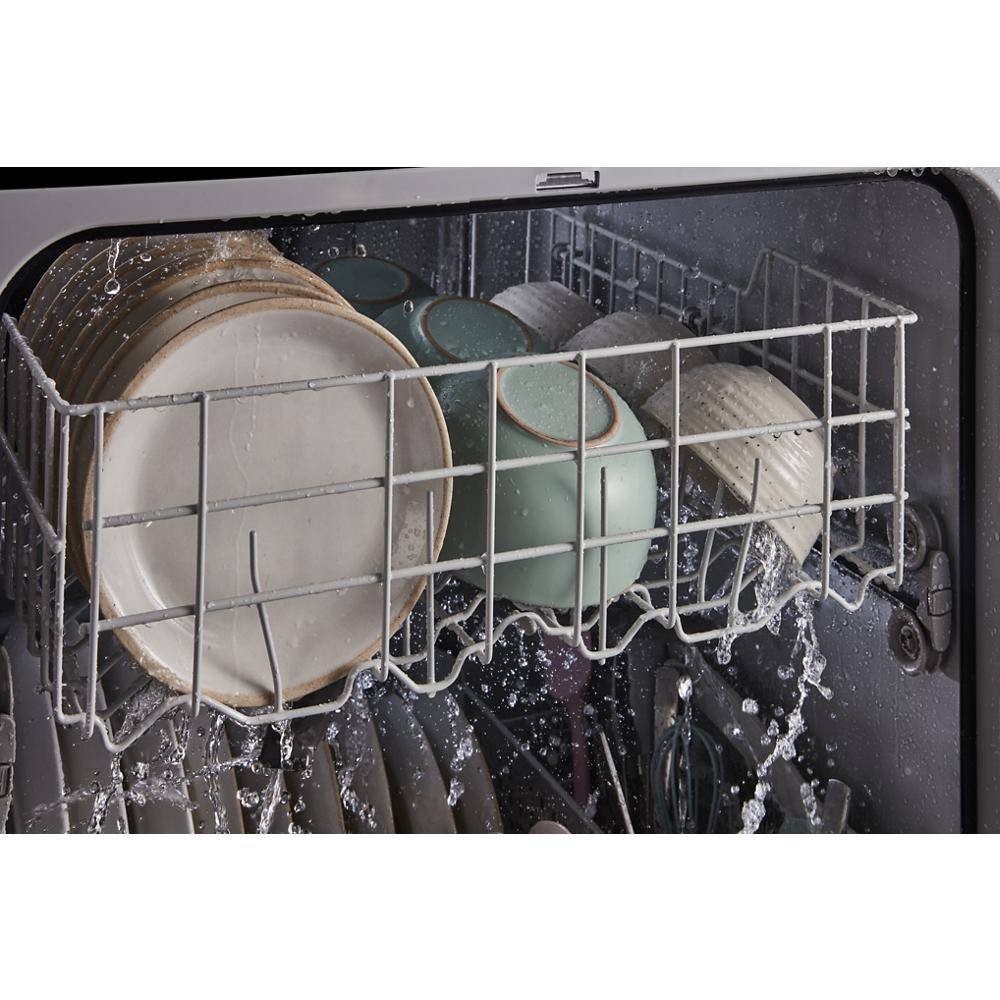 Interior of dishwasher cleaning a load of dishes with water spraying during wash cycle for kitchen appliances