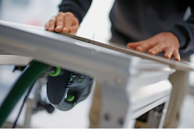 Close-up of a Festool jigsaw base adapter attached to a guide rail for precise woodworking and home improvement cuts