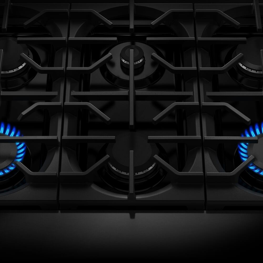 Close-up of six-burner black gas cooktop with blue flames, part of KitchenAid ranges and home improvement tools collection
