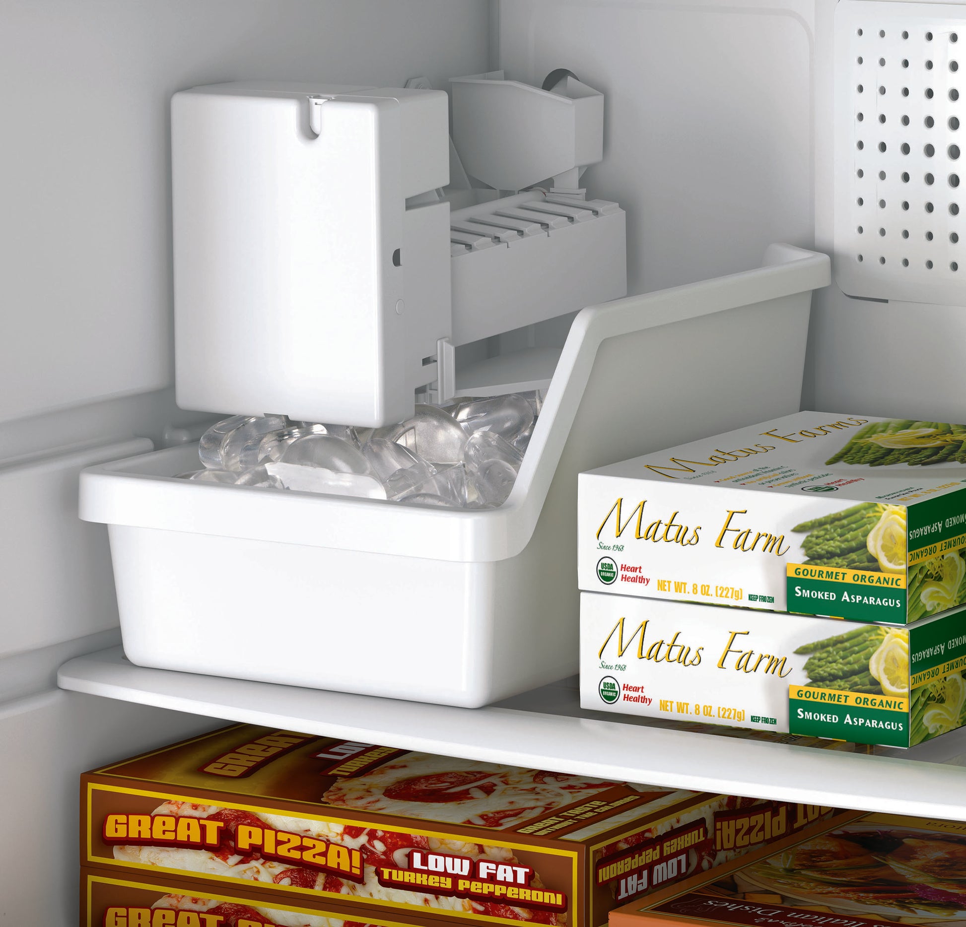 White automatic refrigerator ice maker kit dispensing ice cubes with frozen food boxes inside freezer compartment