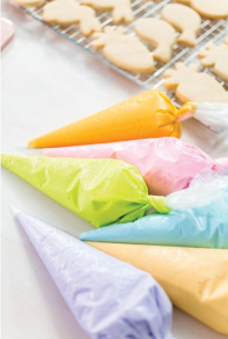 Set of colorful disposable pastry icing bags filled with frosting for cookie decorating and baking tasks