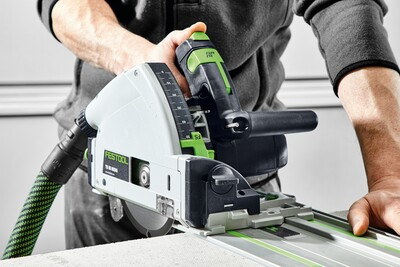 Green and white Festool circular saw cutting a material with precision on a track guide in a home improvement setting