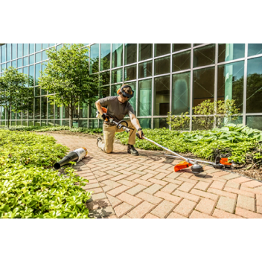 Person wearing safety gear operating a STIHL KM 91 R KombiMotor on brick pathway for home improvement tasks