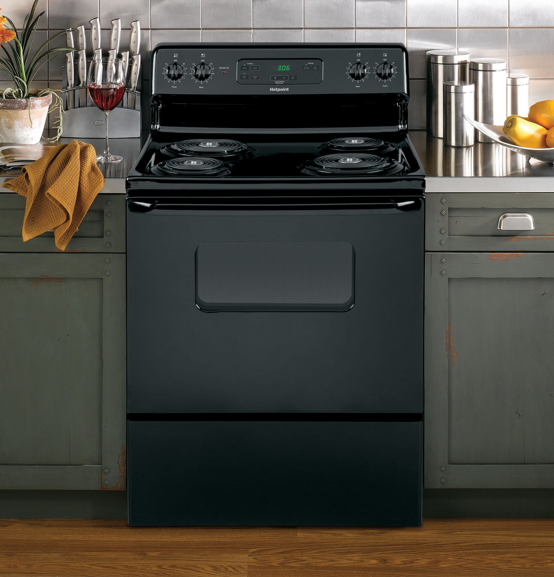 Black free-standing electric range with four coil burners and digital control panel in kitchen setting