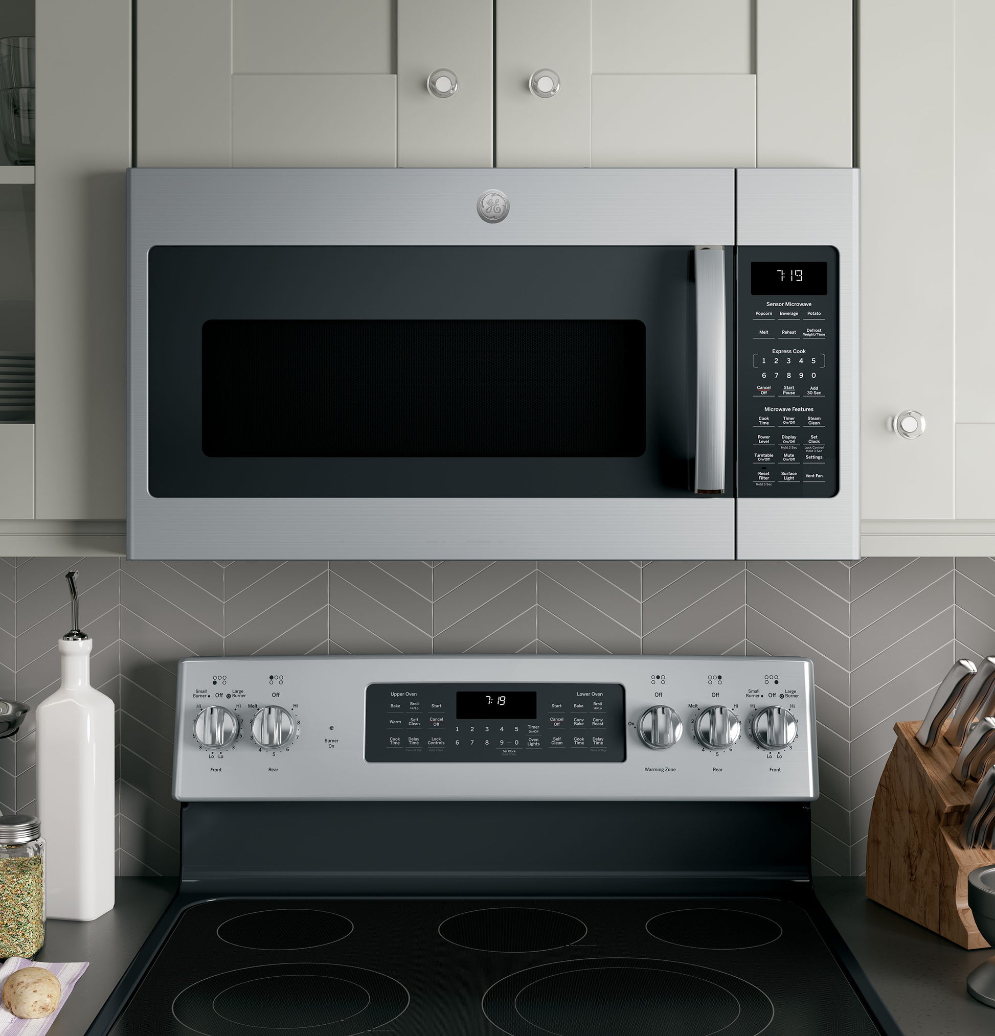 Stainless steel over-the-range microwave with sensor controls installed above electric stove in modern kitchen setting