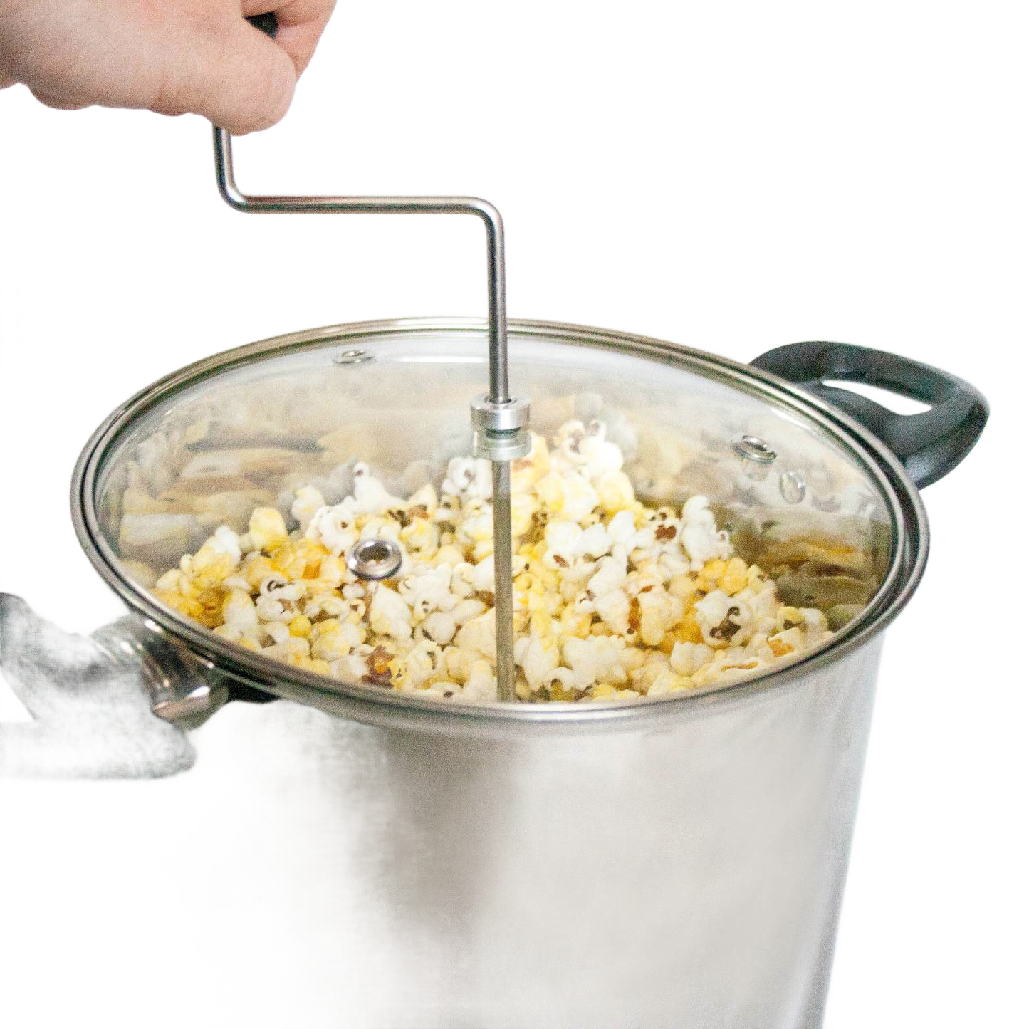Hand turning crank on stainless steel popcorn popper with glass lid, filled with freshly popped popcorn from Small Kitchen Appliances collection