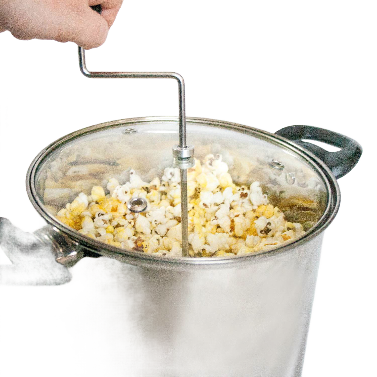 Hand turning crank on stainless steel popcorn popper with glass lid, filled with freshly popped popcorn from Small Kitchen Appliances collection