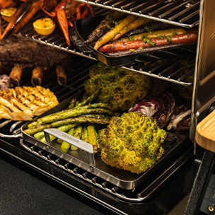 Stainless steel grill tray holding vegetables inside outdoor grill from Traeger grilling accessories collection