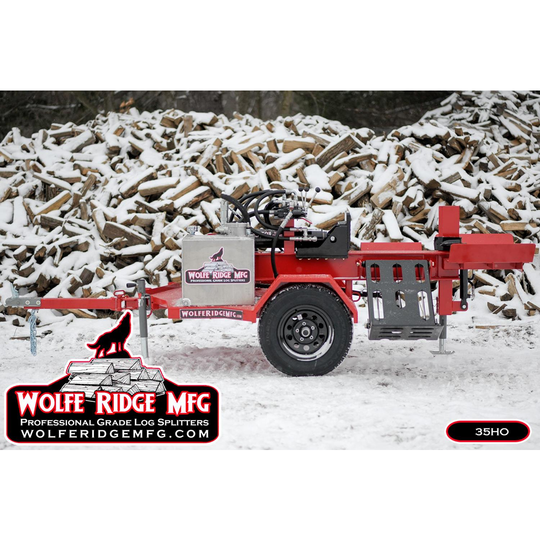 Red and black commercial log splitter trailer with hydraulic components in a snowy outdoor firewood processor setting