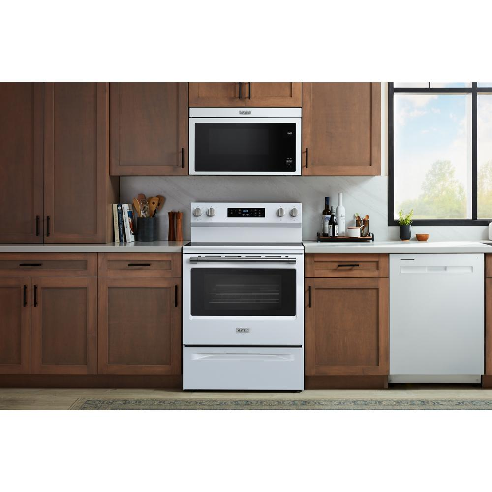 White 30-inch electric range with digital controls and microwave installed above in modern kitchen setting