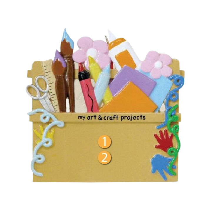 Craft supply box ornament with paintbrushes, scissors, glue, paper, and decorative flowers for Christmas tree décor