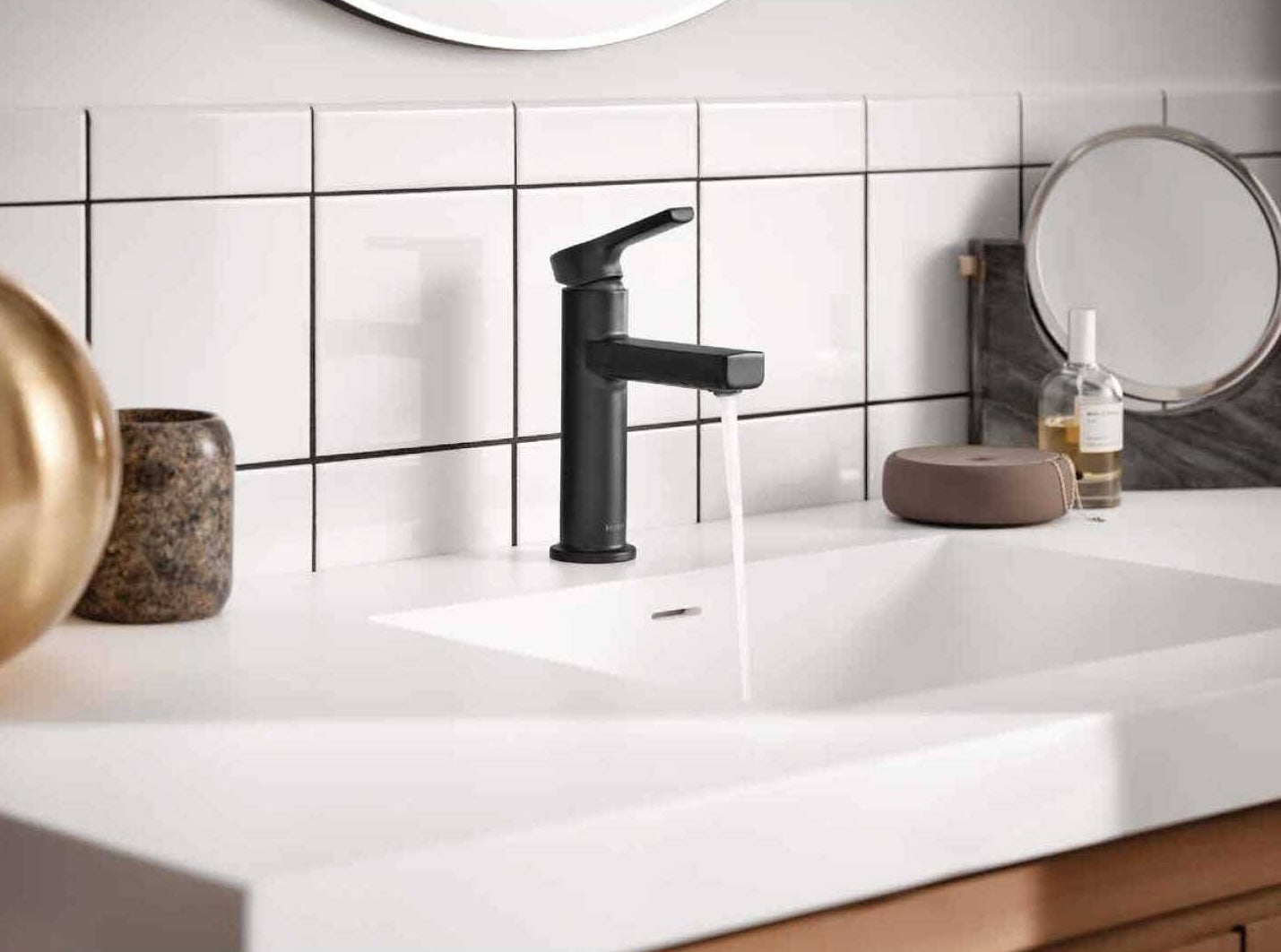 Matte black single-handle lever faucet installed on a white bathroom countertop with running water flow