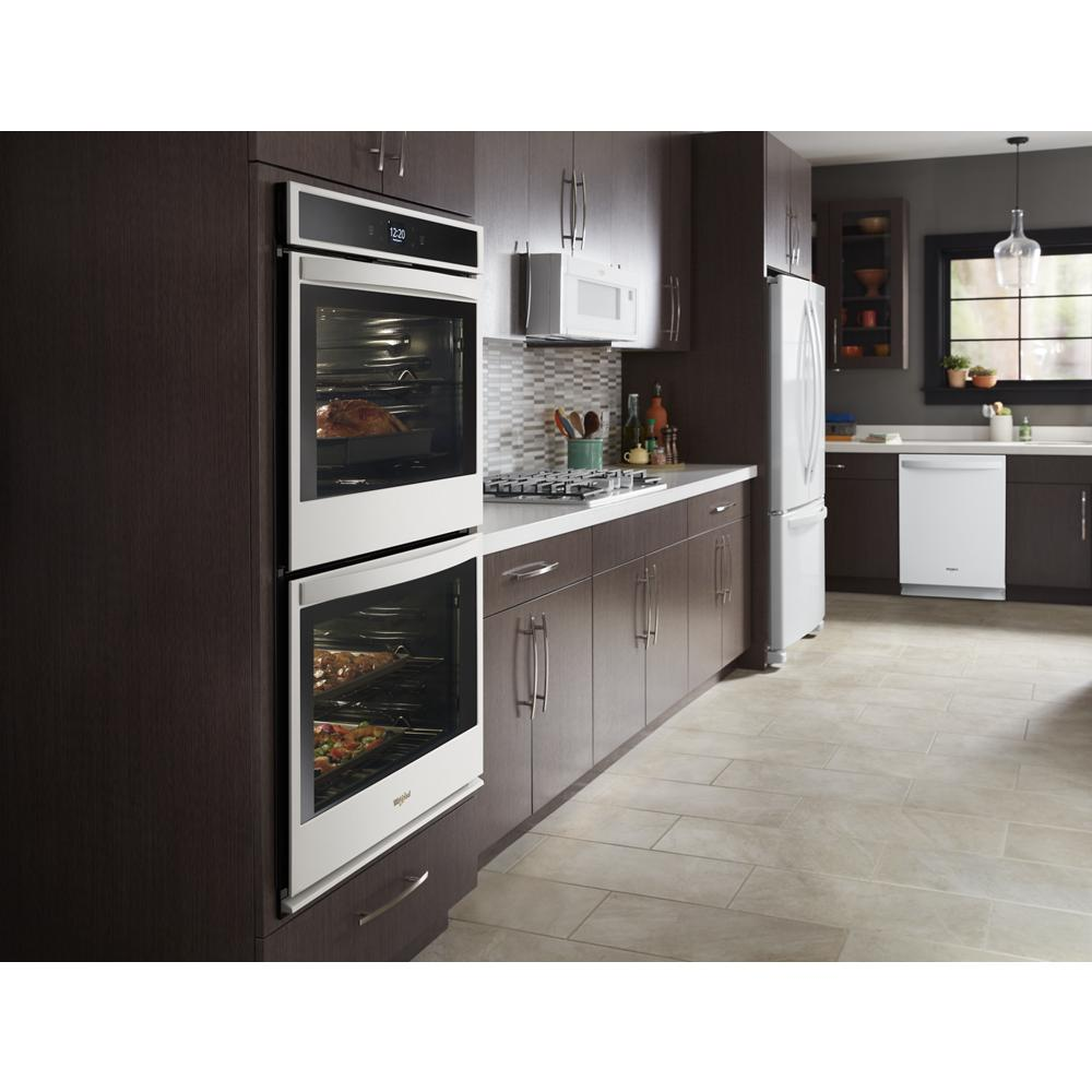 Modern kitchen with built-in double ovens, microwave, white refrigerator, and dishwasher in dark wood cabinets from appliances collection