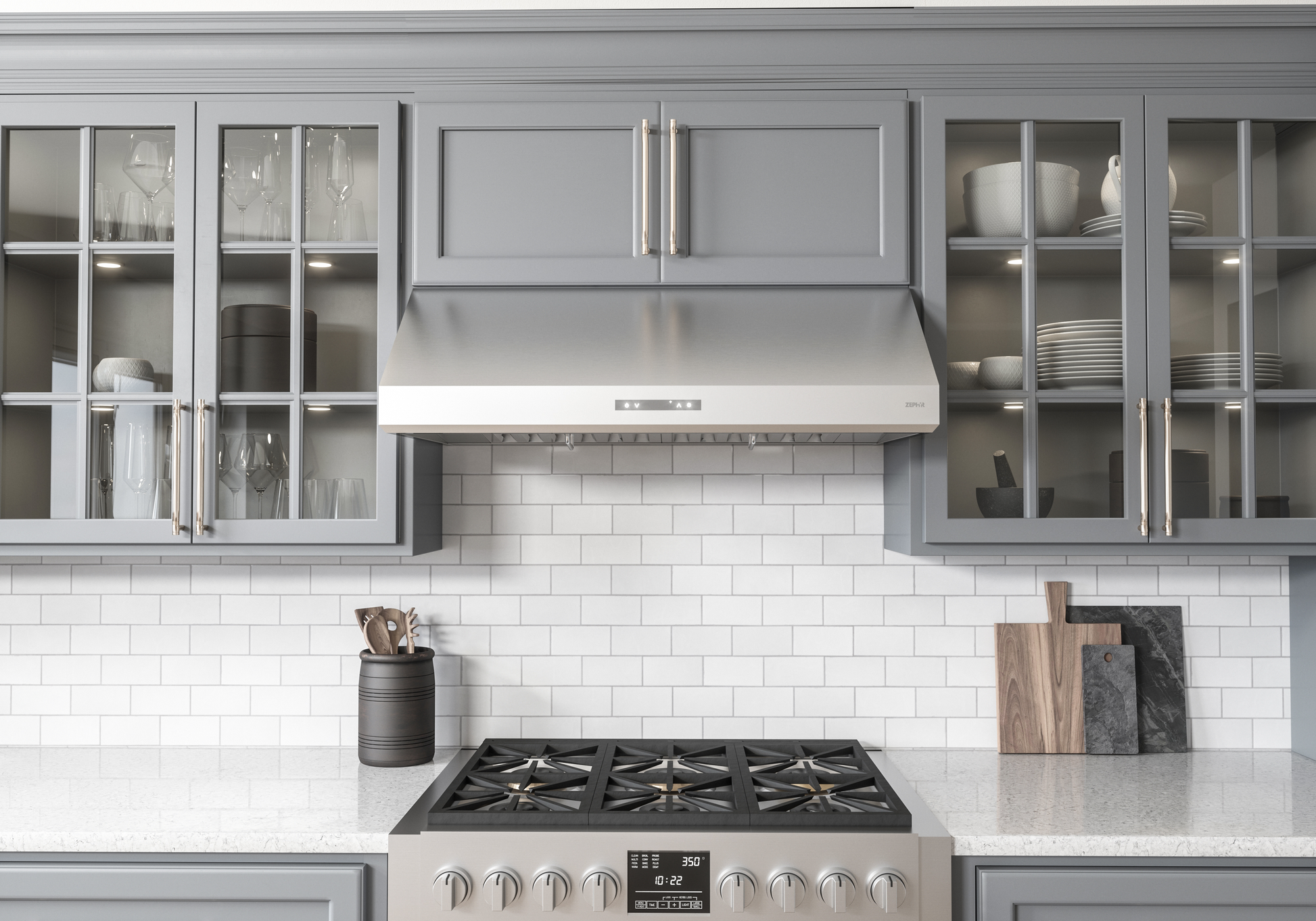 Sleek stainless steel under-cabinet range hood with LED lighting above a gas stove in a modern kitchen with gray cabinetry and white subway tile backsplash, part of Range Hoods, Kitchen & Kitchenware, All Products, and Appliances collections.