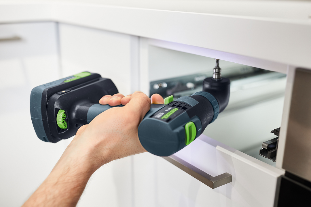 Hand using Festool 576901 TXS 18-Basic cordless drill with angled attachment to install drawer hardware in kitchen cabinet
