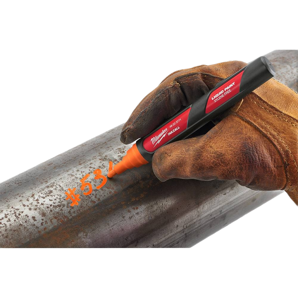 Hand wearing work glove using orange liquid paint marker to write on rusty metal pipe in home improvement tools collection