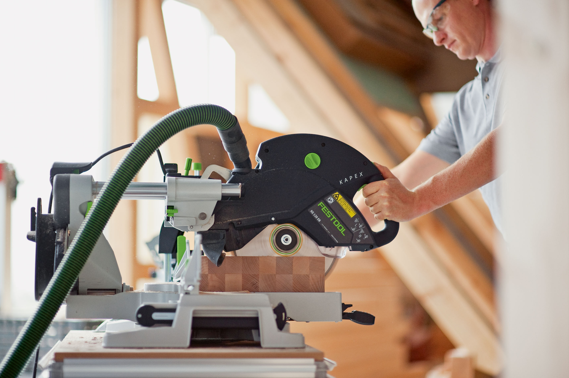 Man using sliding compound miter saw with dust extraction for precise woodworking in power tools and Festool saws collection