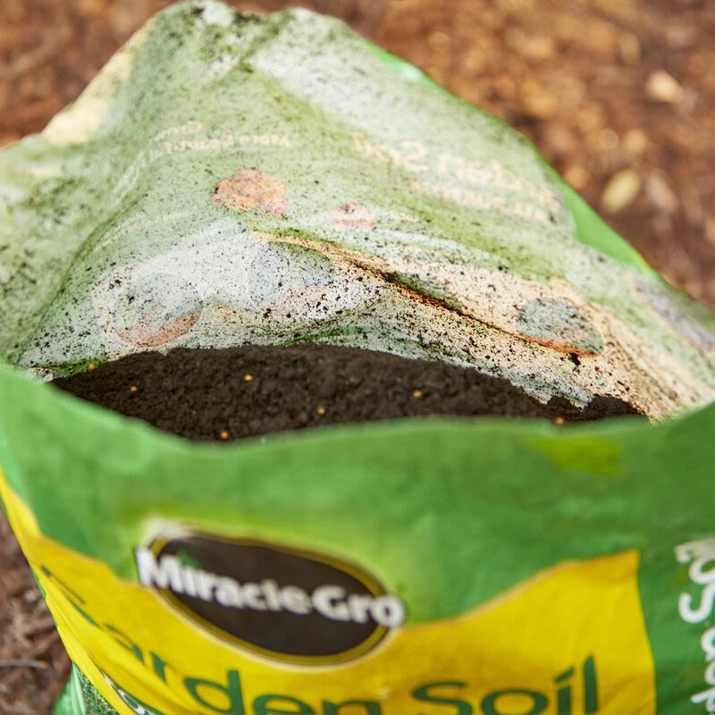 Opened bag of Miracle-Gro garden soil showing rich dark soil inside for landscaping and outdoor living projects